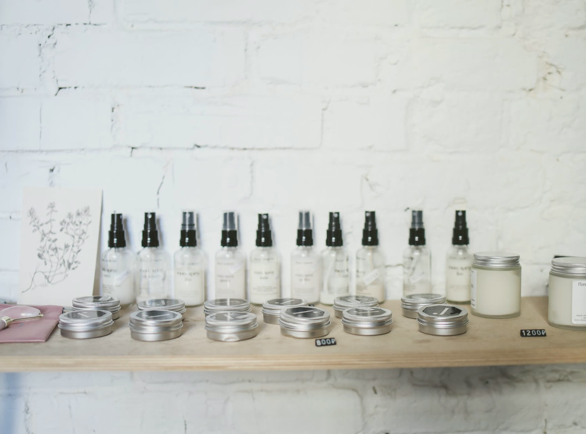 Skincare bottles and tins on a shelf against a white brick wall
